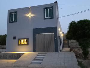 a white house with a window with lights in it at Alnoor Lodgings in Rabwāh