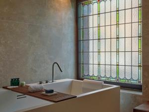 a bathroom with a white tub and a stained glass window at Mandarin Oriental Conservatorium, Amsterdam in Amsterdam