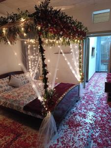 a bedroom with a canopy bed with christmas lights at Alnoor Lodgings in Rabwāh