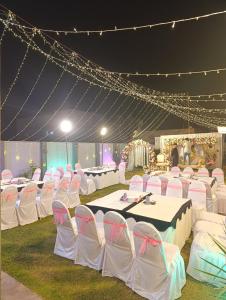 a tent with white chairs and tables and lights at Alnoor Lodgings in Rabwāh