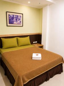 a bedroom with a bed with a towel on it at Grand Kalimas Hotel in Surabaya