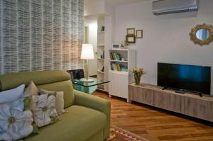 sala de estar con sofá verde y TV de pantalla plana en Madeleine apartments - Residenza Belle Époque, en Milán