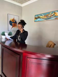 a woman talking on a cell phone at a counter at Ledula Guesthouse in Ramotswa