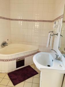 a white bathroom with a tub and a sink at Ledula Guesthouse in Ramotswa