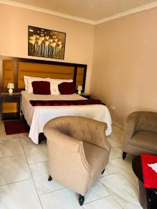 a bedroom with a large bed and two chairs at Ledula Guesthouse in Ramotswa