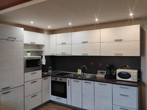 a kitchen with white cabinets and a sink and a microwave at STADIUM 2 Apartments Sandanski in Sandanski +7 photos