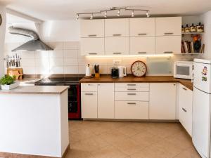 a kitchen with white cabinets and a clock on the counter at Hisa pri Ovcicevih in Komen