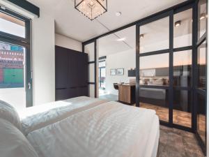 a bedroom with a large white bed and large windows at ELBE6 Apartments in Wittenberge