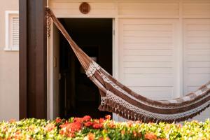 a hammock hanging outside of a house with flowers at Pousada Tropical Ilhas in Aquiraz