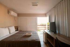 a bedroom with a bed and a flat screen tv at Pousada Tropical Ilhas in Aquiraz