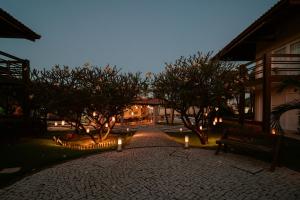 a courtyard with trees and lights in front of a building at Pousada Tropical Ilhas in Aquiraz