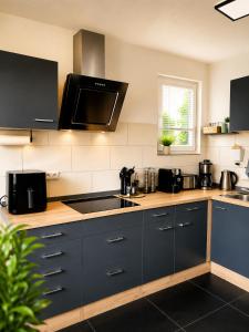 a kitchen with black cabinets and a sink and a window at Ferienwohnung Elya Gartenparadies nahe Events, Outlet und Spa in Bad Münstereifel
