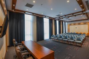 a conference room with chairs and tables and a screen at Jizzax Hotel Tashkent in Tashkent