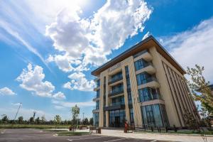 a building with a blue sky and clouds at Jizzax Hotel Tashkent in Tashkent