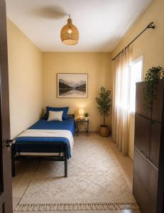 a bedroom with a blue bed and a window at Raha-26 in Al Ghar