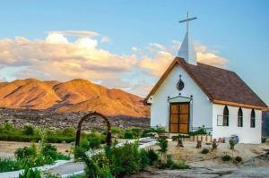 a small white church with a steeple in the desert at Rancho Meling in Camalú