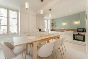 a white kitchen with a wooden table and chairs at Maison Sophie for 10 guests in Pierrefonds