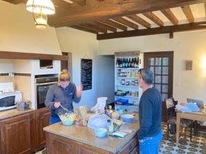 two people standing in a kitchen preparing food at Maison d'hôtes- éco tourisme in Moux-en-Morvan