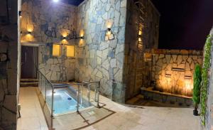 a bathroom with a tub with a stone wall at JebelStay in Al Ḩamrāʼ