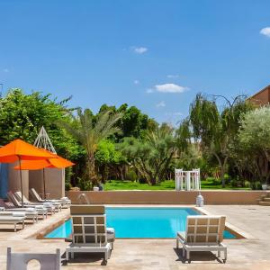 a swimming pool with lounge chairs and an orange umbrella at Palais Jena Hotel & Spa in Marrakesh