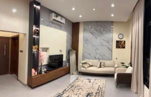 a living room with a couch and a tv at JebelStay in Al Ḩamrāʼ
