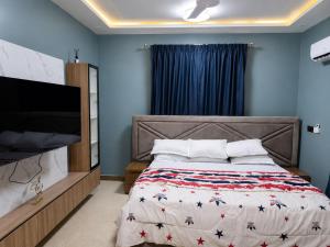 a bedroom with a bed and a flat screen tv at the urban escape in Kwabenyan +2 photos