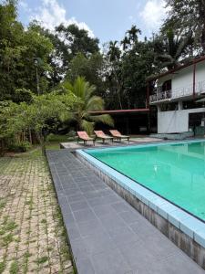 a swimming pool with two chairs next to a building at Nuwanma in Halpatota +6 photos