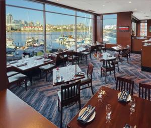 a restaurant with tables and chairs and a view of a harbor at Coast Victoria Hotel & Marina by APA in Victoria