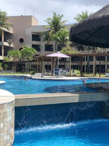 a swimming pool with a fountain in front of a building at Pirâmide Palace Hotel in Natal