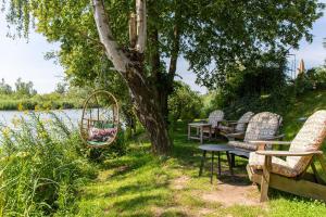 a group of chairs and tables under a tree next to a river at De Zuileshoeve in Dordrecht