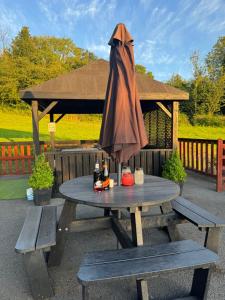 a picnic table with an umbrella on top of it at Kabin in the woods with Hot Tub in Llandybie
