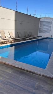 a swimming pool with chairs next to a building at Studio com sacada, piscina e academia a 25 min Aeroporto GRU in São Paulo