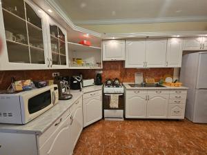a kitchen with white cabinets and white appliances at Party Vendégház in Hajdúszoboszló