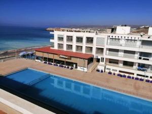 a hotel with a swimming pool in front of the ocean at Cozy apartment adana in Aourir