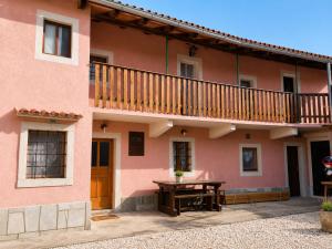 a pink house with a wooden table and a balcony at Hisa pri Ovcicevih in Komen