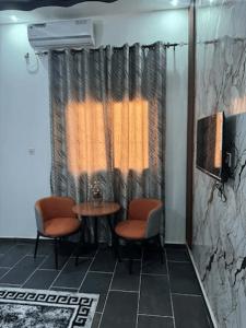 a room with two chairs and a table and a window at Hôtel La Parisienne in Louga