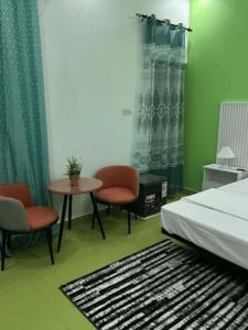 a bedroom with a bed and two chairs and a table at Hôtel La Parisienne in Louga