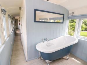 a bathroom with a tub and a mirror on the wall at Clifftop Carriage in Aberporth +31 photos