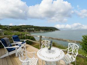 a table and chairs on a deck with a view of the ocean at Clifftop Carriage in Aberporth