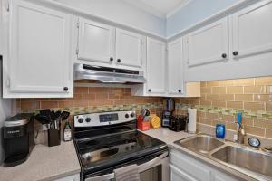 a kitchen with white cabinets and a stove and a sink at Beach Getaway w Pool & Private Balcony in Atlantic Beach