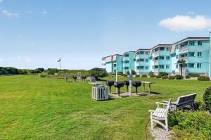 a park with benches and tables in front of a building at Beach Getaway w Pool & Private Balcony in Atlantic Beach