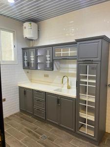 a kitchen with gray cabinets and a sink at شالية خاص in Khamis Mushayt