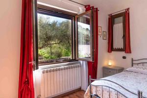 a bedroom with a bed and a window with red curtains at Casa Konny in Gonnostramatza