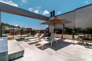a patio with chairs and tables and an umbrella at Apto 2 dormitórios com piscina-Praia de Bombinhas. in Bombinhas