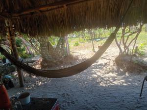 a hammock hanging from a thatch hut at Hostel Rústico in Barreirinhas