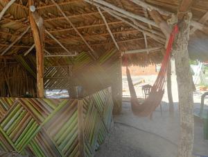 a hammock in a straw hut with a table at Hostel Rústico in Barreirinhas +9 photos