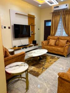 a living room with couches and a flat screen tv at ACCENT HOMES Apartment in Asaba