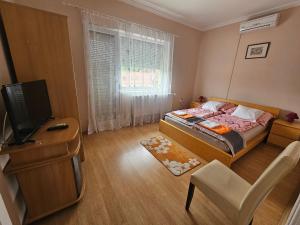a small bedroom with a bed and a television at Party Vendégház in Hajdúszoboszló