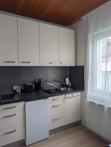 a kitchen with white cabinets and a sink and a window at Royal Racing Suite Top 4 near Red Bull Ring in Judenburg
