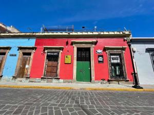 a red building with a green door on a street at Atelier Oaxaca in Oaxaca City